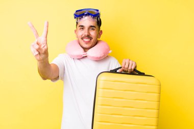 Genç İspanyol adam gülümsüyor ve mutlu görünüyor, zafer ya da barış işareti yapıyor. seyahat kavramı