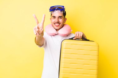 Genç İspanyol adam gülümsüyor ve arkadaş canlısı görünüyor, iki numarayı gösteriyor. seyahat kavramı