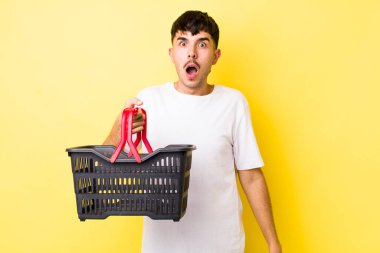 Genç İspanyol adam çok şaşırmış ya da şaşkın görünüyor. boş alışveriş sepeti kavramı