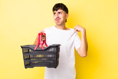 Genç İspanyol adam stresli, endişeli, yorgun ve hayal kırıklığına uğramış hissediyor. boş alışveriş sepeti kavramı