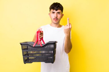 Genç İspanyol adam kızgın, sinirli, asi ve agresif hissediyor. boş alışveriş sepeti kavramı