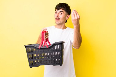 Genç İspanyol adam kapiş ya da para hareketi yapıyor, sana ödemeni söylüyor. boş alışveriş sepeti kavramı