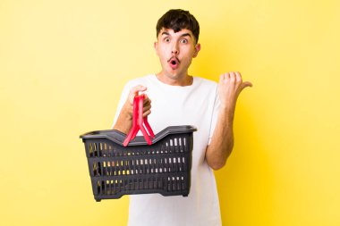 Genç İspanyol adam inançsızlıktan şaşkın şaşkın bakıyor. boş alışveriş sepeti kavramı