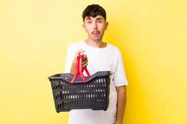 Genç İspanyol bir adam üzgün ve mızmızlanıyor. Mutsuz bir bakışı var ve ağlıyor. boş alışveriş sepeti kavramı