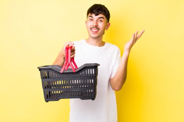 Genç İspanyol adam mutlu hissediyor, bir çözüm ya da fikir bulduğuna şaşırıyor. boş alışveriş sepeti kavramı