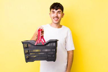 Genç İspanyol adam mutlu ve hoş bir şekilde şaşırmış görünüyor. boş alışveriş sepeti kavramı