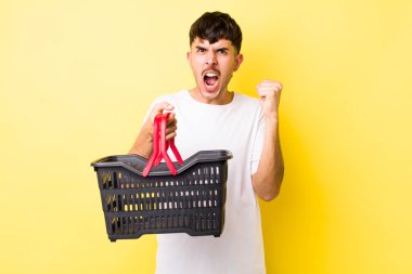 Genç İspanyol adam sinirli bir ifadeyle agresif bir şekilde bağırıyor. boş alışveriş sepeti kavramı