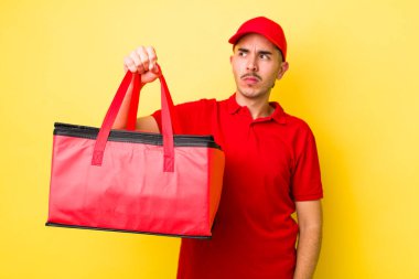 Genç İspanyol bir adam üzgün, üzgün ya da kızgın hissediyor ve yan tarafa bakıyor. Pizza dağıtımı kavramı