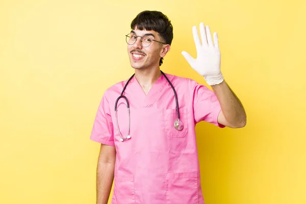 Jonge Spaanse Man Glimlacht Vrolijk Zwaait Met Zijn Hand Verwelkomt — Stockfoto