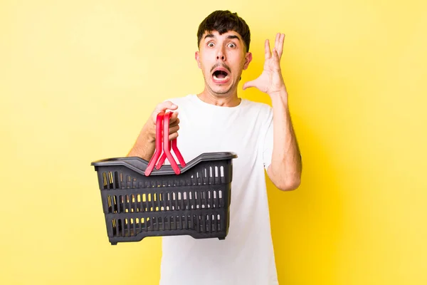Young Hispanic Man Screaming Hands Air Empty Shopping Basket Concept — Stock Photo, Image