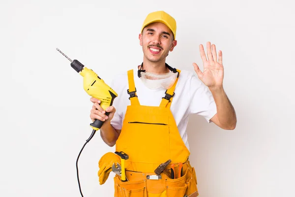 Hispanic Handyman Smiling Happily Waving Hand Welcoming Greeting You Drill — Stock Photo, Image