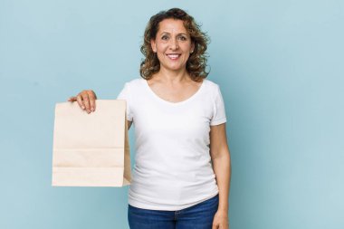 Orta yaşlı bir kadın mutlu bir şekilde gülümsüyor, eli kalçasında ve kendinden emin. konsepti kaldır