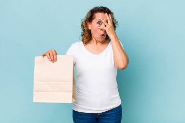 Orta yaşlı bir kadın şok olmuş, korkmuş ya da korkmuş görünüyor, yüzünü elleriyle kapatıyor. konsepti kaldır