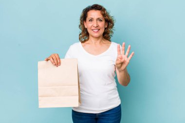 Orta yaşlı kadın gülümsüyor ve arkadaş canlısı görünüyor, dört numarayı gösteriyor. konsepti kaldır