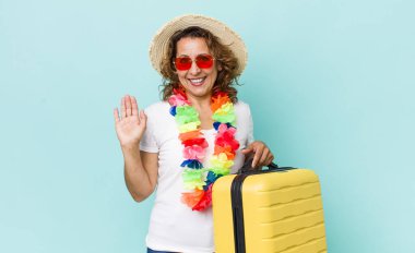 Orta yaşlı bir kadın mutlu bir şekilde gülümsüyor, el sallıyor, sizi selamlıyor ve selamlıyor. Yaz tatili konsepti