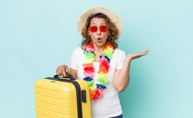 Orta yaşlı kadın şaşırmış ve şok olmuş görünüyor. Çenesi düşmüş ve elinde bir nesne var. Yaz tatili konsepti