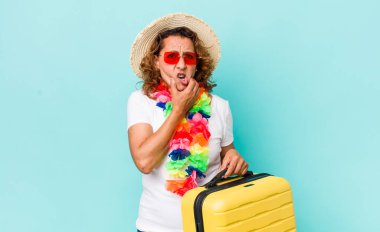 Orta yaşlı kadın, ağzı ve gözleri sonuna kadar açık ve elleri çenesinde. Yaz tatili konsepti