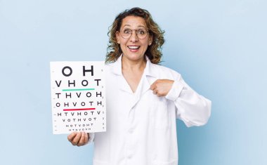 Orta yaşlı bir kadın kendini mutlu hissediyor ve heyecanlı bir şekilde kendini işaret ediyor. vizyon testi kavramı