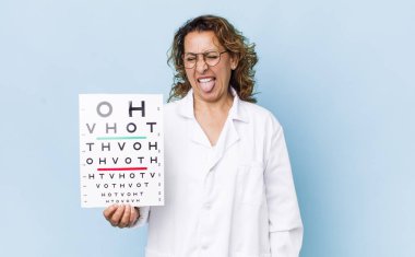 Neşeli ve asi tavırları olan orta yaşlı bir kadın şaka yapıyor ve dilini dışarı çıkarıyor. vizyon testi kavramı