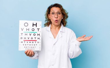 Orta yaşlı kadın şaşırmış ve şok olmuş görünüyor. Çenesi düşmüş ve elinde bir nesne var. vizyon testi kavramı