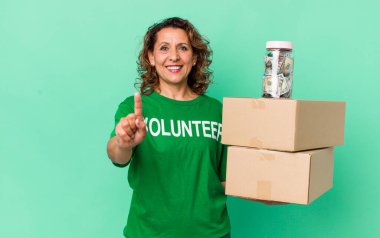 Orta yaşlı bir kadın gülümsüyor ve arkadaş canlısı görünüyor. Bir numarayı gösteriyor. gönüllü ve bağış konsepti