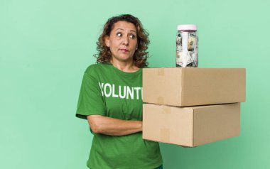 Orta yaşlı bir kadın omuz silkiyor, kafası karışık ve kararsız. gönüllü ve bağış konsepti