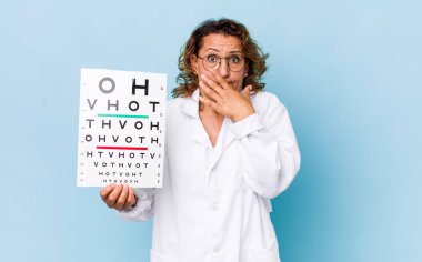 Orta yaşlı bir kadın şok olmuş bir şekilde elleri ile ağzını kapatıyor. vizyon testi kavramı