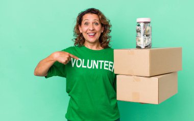 Orta yaşlı bir kadın kendini mutlu hissediyor ve heyecanlı bir şekilde kendini işaret ediyor. gönüllü ve bağış konsepti