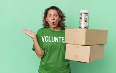 Orta yaşlı kadın şaşırmış ve şok olmuş görünüyor. Çenesi düşmüş ve elinde bir nesne var. gönüllü ve bağış konsepti