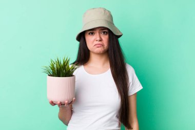 Genç bir kadın üzgün ve mızmızlanıyor. Mutsuz bir bakışı var ve ağlıyor. bitki kavramı