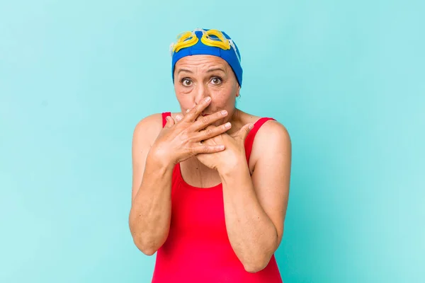 middle age woman covering mouth with hands with a shocked. swimming concept
