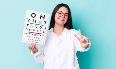 Gülümseyen ve mutlu görünen genç bir kadın zafer ya da barış işareti yapıyor. optik görüş testi konsepti