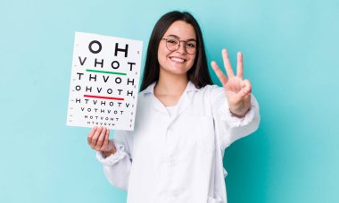 Genç yetişkin kadın gülümsüyor ve arkadaş canlısı görünüyor, üç numarayı gösteriyor. optik görüş testi konsepti