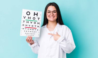 Genç yetişkin bir kadın neşeyle gülümsüyor, mutlu hissediyor ve bir tarafı işaret ediyor. optik görüş testi konsepti