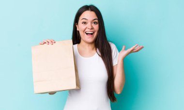 Genç bir kadın kendini mutlu hissediyor ve inanılmaz bir şeye hayret ediyor. konsepti kaldır