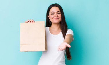 Genç yetişkin bir kadın arkadaşça gülümsüyor ve bir konsept sunuyor. konsepti kaldır