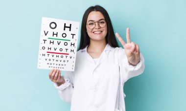 Genç yetişkin kadın gülümsüyor ve arkadaş canlısı görünüyor, iki numarayı gösteriyor. optik görüş testi konsepti