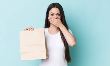 Genç, yetişkin bir kadın şok olmuş bir şekilde elleriyle ağzını kapatıyor. konsepti kaldır