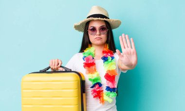 Genç bir kadın ciddi görünüyor. Avuç içini gösteriyor. Durdurma hareketi yapıyor. Yaz tatili konsepti