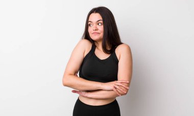 Genç bir kadın omuz silkiyor, kafası karışık ve kararsız. fitness konsepti