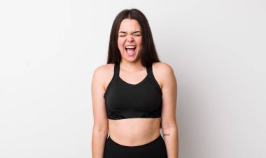 Genç yetişkin bir kadın agresif bir şekilde bağırıyor, çok kızgın görünüyor. fitness konsepti
