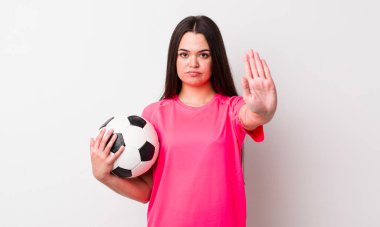 Genç bir kadın ciddi görünüyor. Avuç içini gösteriyor. Durdurma hareketi yapıyor. futbol kavramı