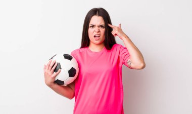 Genç yetişkin bir kadın kafası karışık ve şaşkın hissediyor, senin deli olduğunu gösteriyor. futbol kavramı