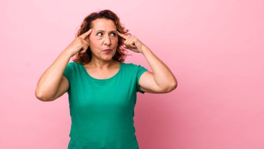 Orta yaşlı İspanyol bir kadın kafası karışık ya da şüpheci, bir fikre odaklanmış, çok düşünüyor, kenarda yer arıyor.