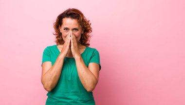 Orta yaşlı İspanyol kadın mutlu, neşeli, şanslı ve şaşkın görünüyor iki eliyle ağzını kapatıyor.