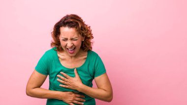 Orta yaşlı İspanyol bir kadın komik bir şakaya yüksek sesle gülüyor, mutlu ve neşeli hissediyor, eğleniyor.