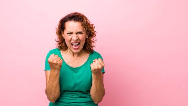 Orta yaşlı Latin bir kadın sinirli, sinirli, sinirli ve yumruklarını sıkmış bir şekilde bağırıyor.