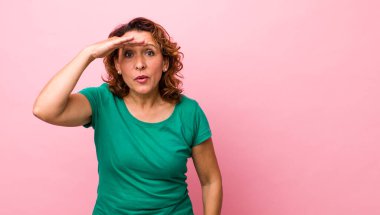 Orta yaşlı İspanyol bir kadın şaşkınlık ve şaşkınlık içinde bakıyor. Alnı açık, uzaklara bakıyor, izliyor ya da arıyor.