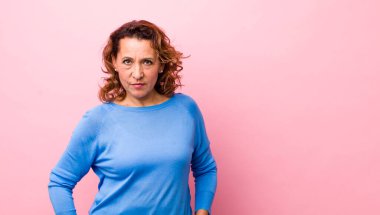 Orta yaşlı İspanyol bir kadın gururlu, kendinden emin, havalı, küstah ve kibirli görünüyor, gülümsüyor, başarılı hissediyor.