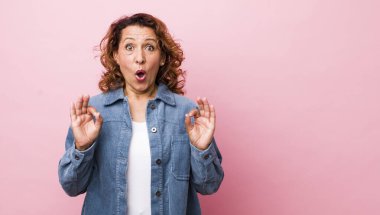 Orta yaşlı İspanyol kadın şok olmuş, şaşırmış ve şaşırmış hissediyor. Onaylıyor. İki eliyle işaret veriyor.